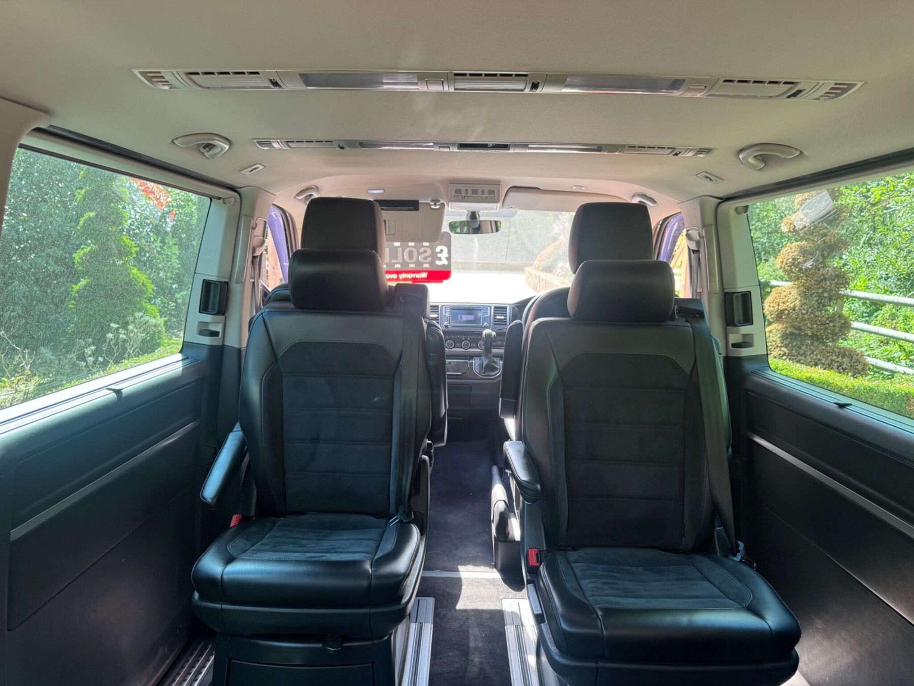 Inside a Volkswagen Caravelle Executive: the rear leather captain's chairs looking forward through the cabin to the front seats